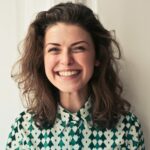 Portrait of a joyful brunette woman with a vibrant smile indoors, capturing happiness and positivity.